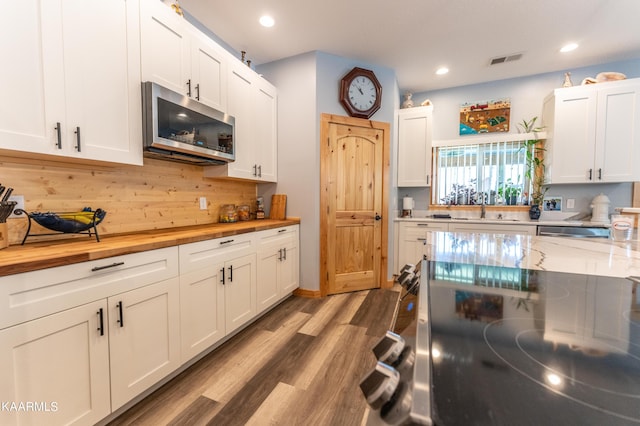 kitchen with white cabinetry, light hardwood / wood-style flooring, sink, and light stone counters