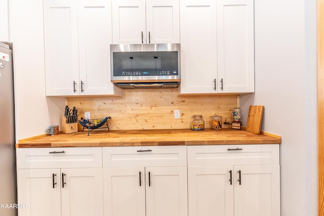 bar with white cabinets, butcher block countertops, stainless steel appliances, and tasteful backsplash