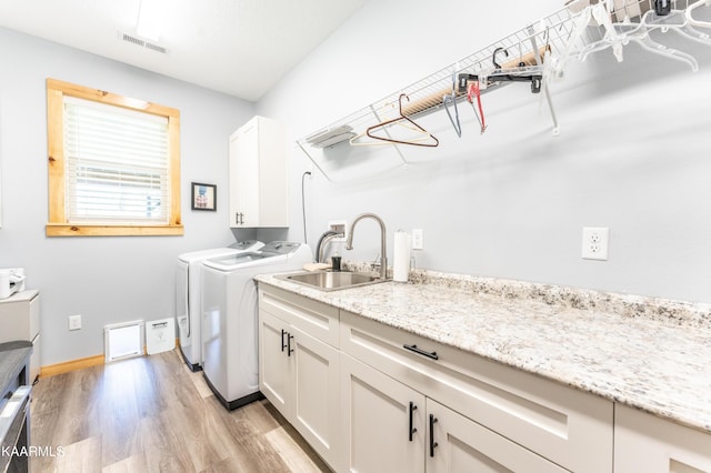 washroom with light wood-type flooring, sink, cabinets, separate washer and dryer, and washer hookup