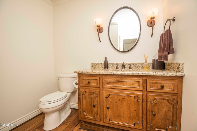 bathroom with toilet, vanity, a baseboard heating unit, wood-type flooring, and ornamental molding