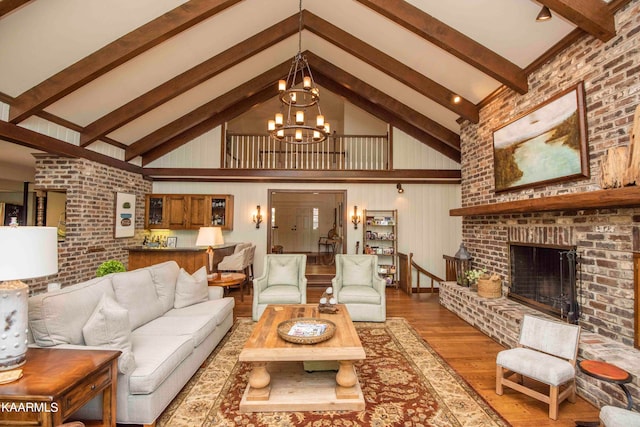 living room with hardwood / wood-style floors, high vaulted ceiling, a notable chandelier, a brick fireplace, and beam ceiling