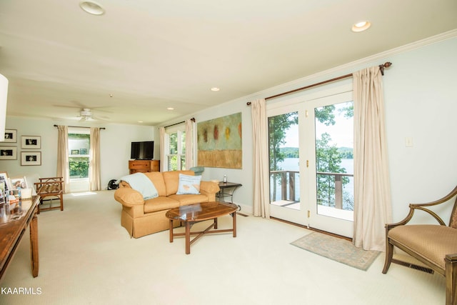 living room featuring crown molding, a healthy amount of sunlight, and light colored carpet