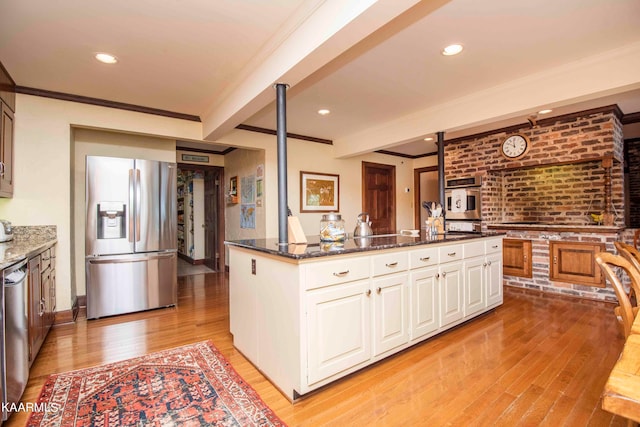 kitchen featuring white cabinetry, appliances with stainless steel finishes, light hardwood / wood-style flooring, and dark stone countertops