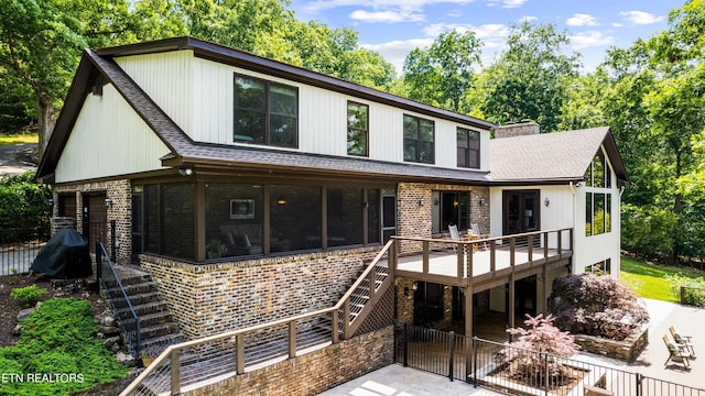 view of front of house with a patio area, a wooden deck, and a sunroom