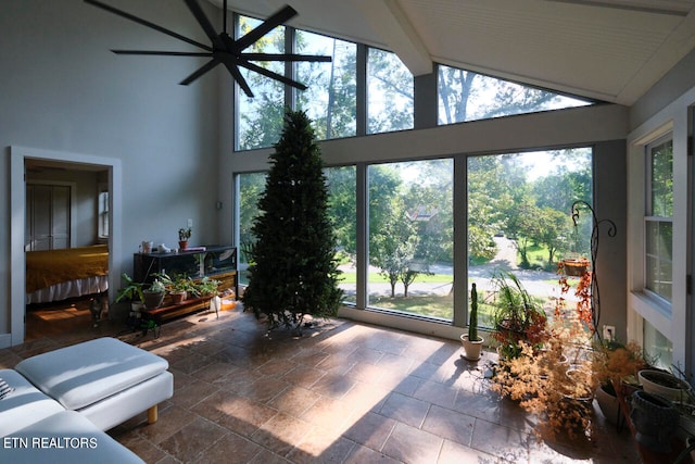 interior space with ceiling fan and vaulted ceiling with beams