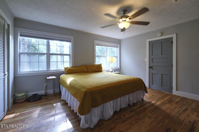 bedroom featuring a textured ceiling, dark hardwood / wood-style floors, a closet, crown molding, and ceiling fan