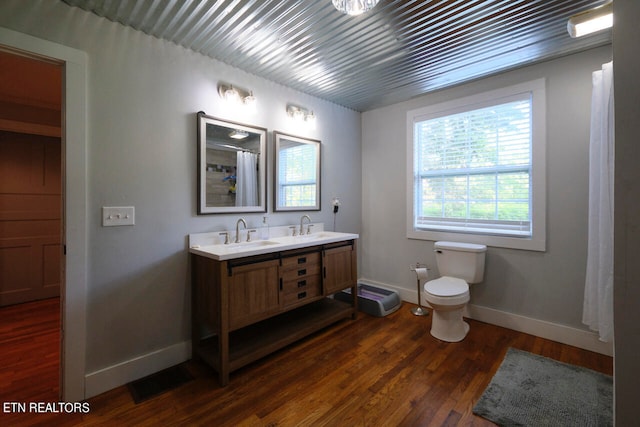 bathroom featuring vanity, toilet, wood-type flooring, and a healthy amount of sunlight