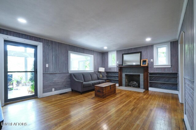 living room featuring wooden walls, wood-type flooring, and a fireplace