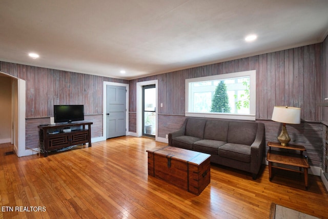 living room with plenty of natural light, wooden walls, and hardwood / wood-style flooring