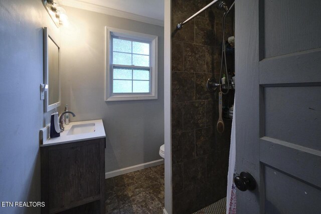 bathroom featuring toilet, a tile shower, ornamental molding, and vanity