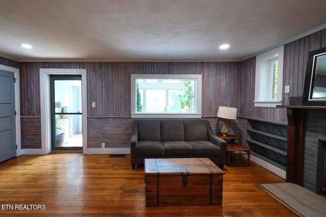 living room with hardwood / wood-style floors, plenty of natural light, a fireplace, and wood walls