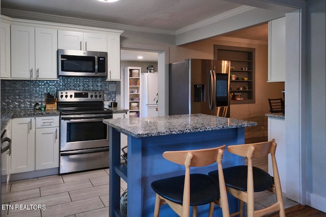 kitchen featuring stainless steel appliances, dark stone counters, white cabinets, and light hardwood / wood-style floors