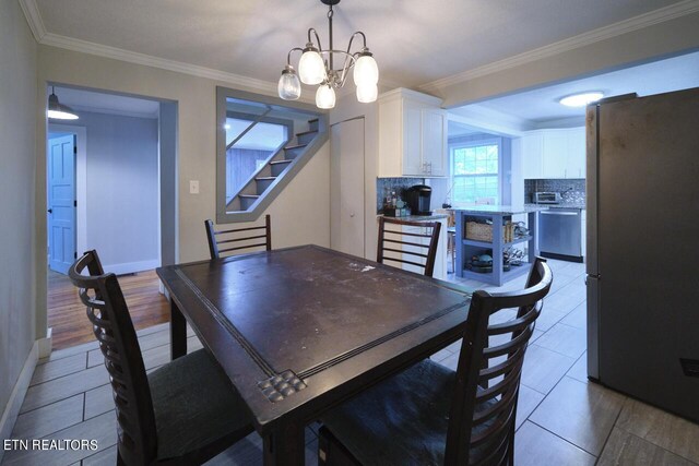 dining area with ornamental molding, an inviting chandelier, and light hardwood / wood-style floors