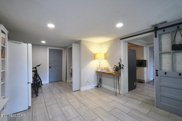 interior space featuring light hardwood / wood-style flooring, a barn door, white refrigerator, black fridge, and ornamental molding