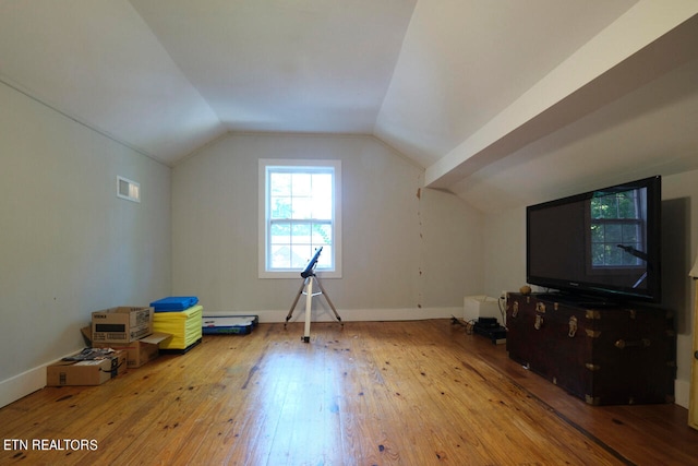 additional living space featuring light wood-type flooring and vaulted ceiling