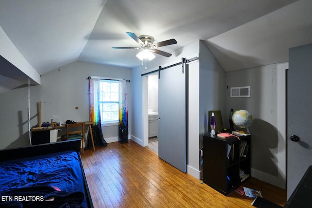 bedroom featuring connected bathroom, ceiling fan, lofted ceiling, hardwood / wood-style flooring, and a barn door