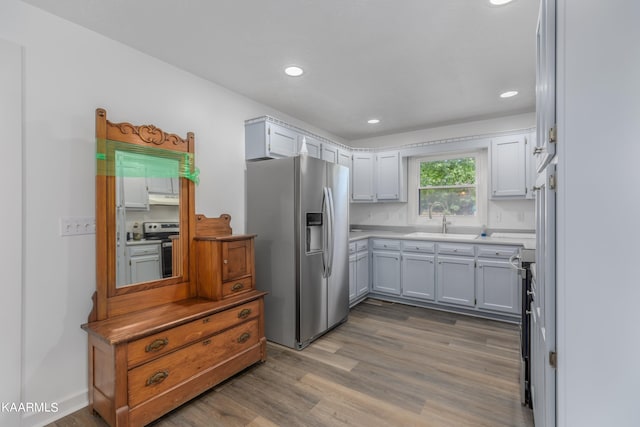 kitchen with white cabinets, hardwood / wood-style floors, appliances with stainless steel finishes, and sink