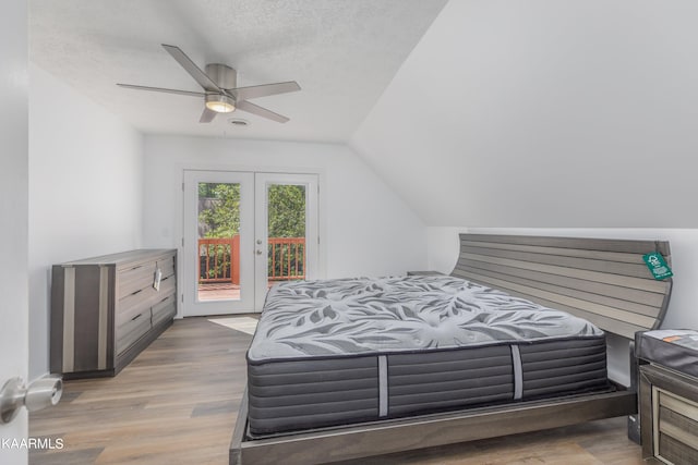 bedroom with access to exterior, ceiling fan, vaulted ceiling, a textured ceiling, and hardwood / wood-style flooring