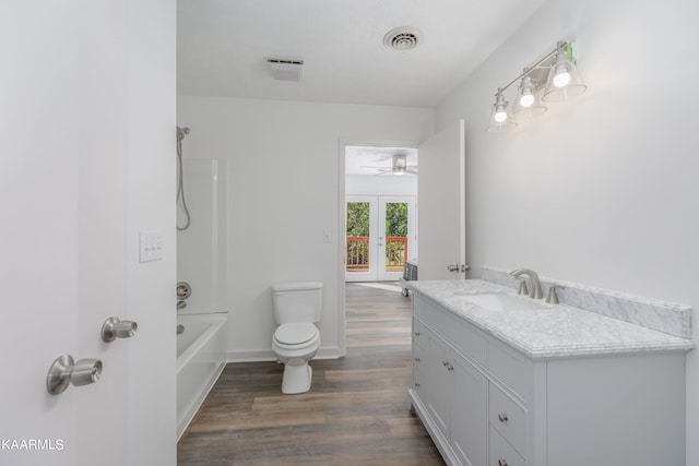 full bathroom featuring washtub / shower combination, wood-type flooring, toilet, vanity, and french doors