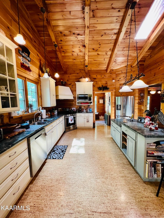 kitchen with appliances with stainless steel finishes, decorative light fixtures, white cabinetry, and wooden walls