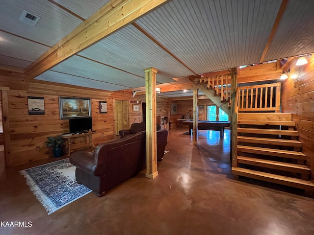 living room featuring concrete floors, beamed ceiling, ornate columns, and wood walls