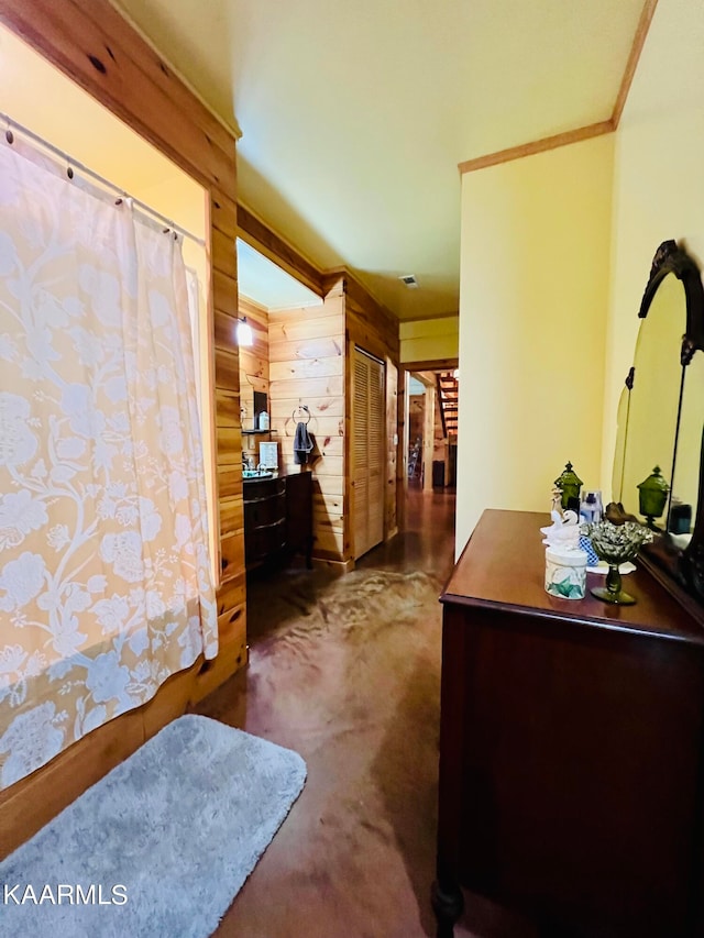 carpeted bedroom featuring wood walls, a closet, and ornamental molding