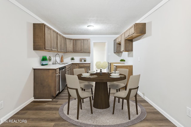 dining room with dark wood-type flooring, a textured ceiling, ornamental molding, and sink