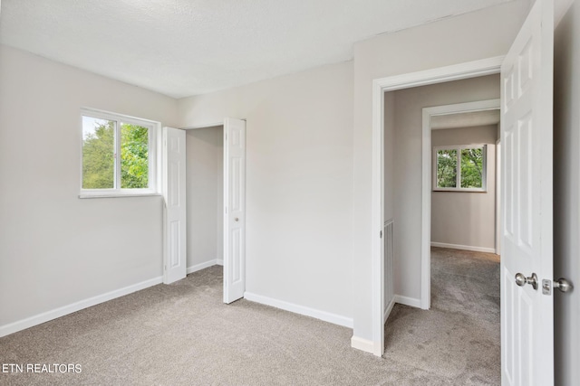 unfurnished bedroom featuring light carpet and multiple windows