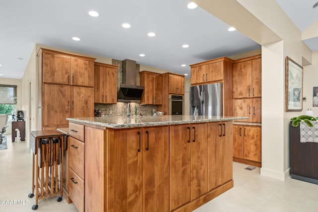 kitchen with light stone countertops, light tile flooring, wall chimney exhaust hood, stainless steel appliances, and tasteful backsplash