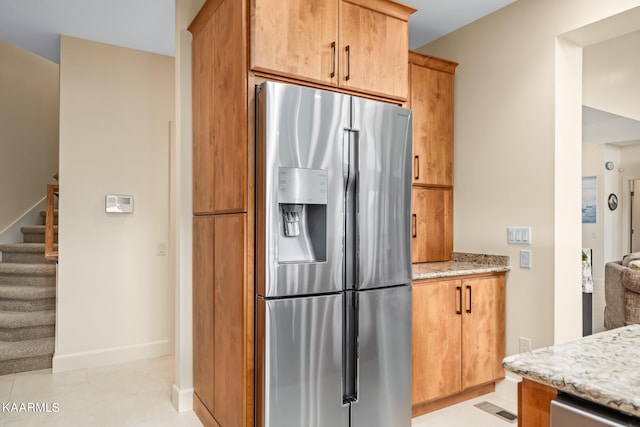 kitchen with light tile flooring, stainless steel appliances, and light stone counters