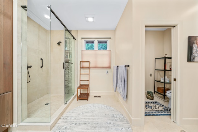 bathroom featuring toilet, tile floors, and a shower with shower door