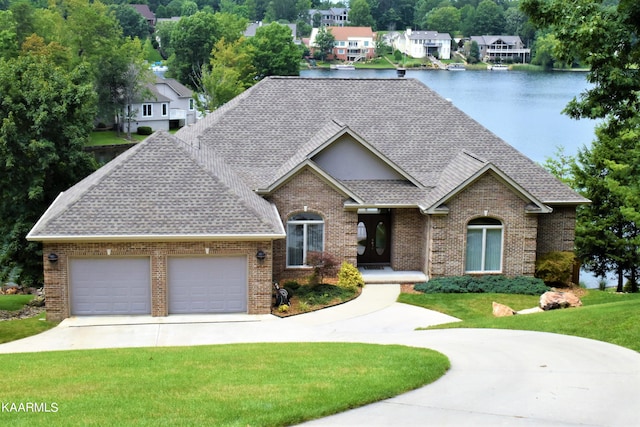 view of front of property featuring a front yard, a garage, and a water view