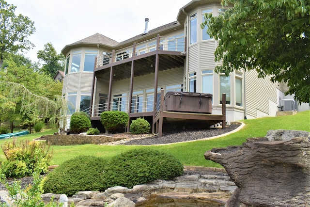 back of house featuring central AC unit, a balcony, a wooden deck, and a lawn