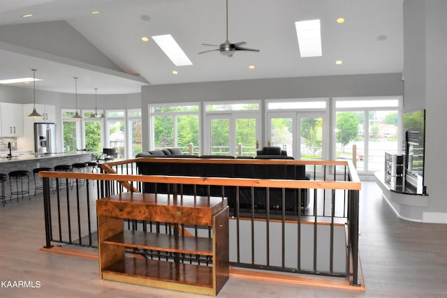 interior space featuring ceiling fan, a skylight, a healthy amount of sunlight, and light hardwood / wood-style flooring