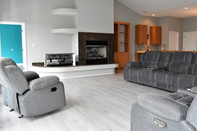 living room with high vaulted ceiling and light wood-type flooring