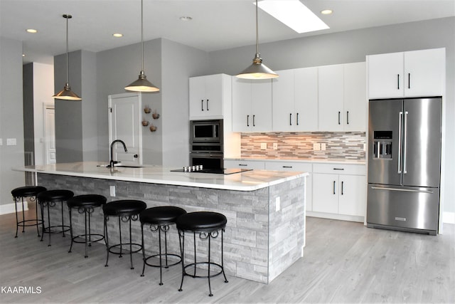 kitchen with a kitchen island with sink, stainless steel appliances, light wood-type flooring, and sink