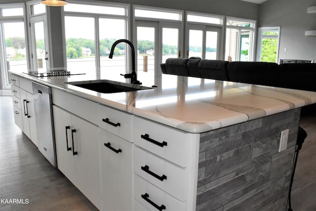 kitchen featuring dark hardwood / wood-style floors, sink, white cabinets, a center island, and light stone counters