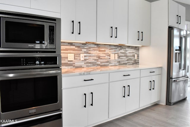 kitchen with backsplash, white cabinetry, appliances with stainless steel finishes, and light hardwood / wood-style floors