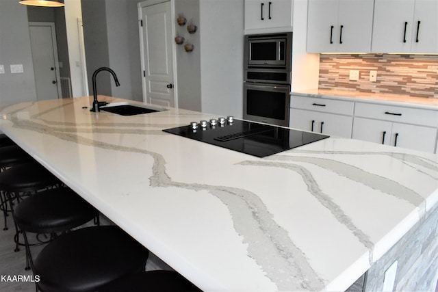 kitchen with backsplash, sink, light stone counters, and stainless steel appliances