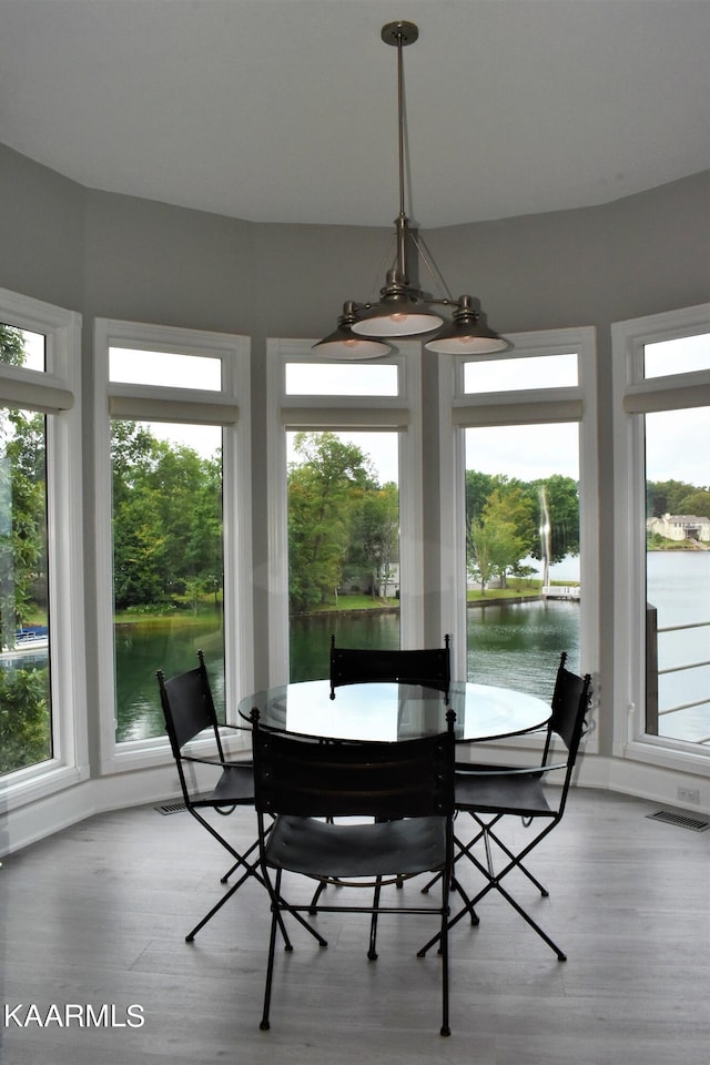 sunroom featuring plenty of natural light, a water view, and a notable chandelier