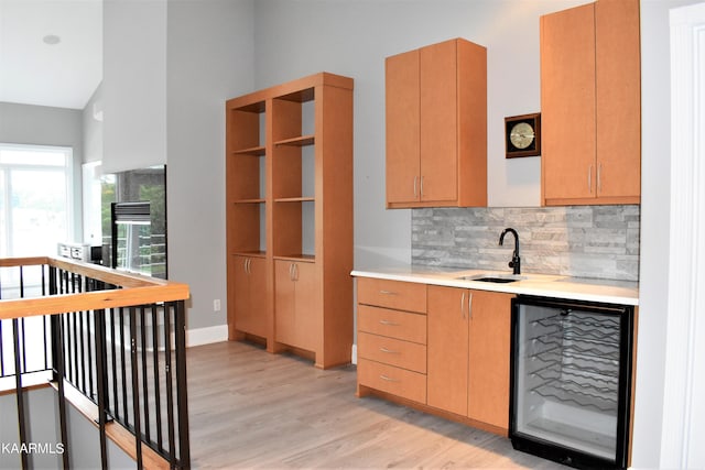 kitchen featuring high vaulted ceiling, light hardwood / wood-style floors, wine cooler, backsplash, and sink