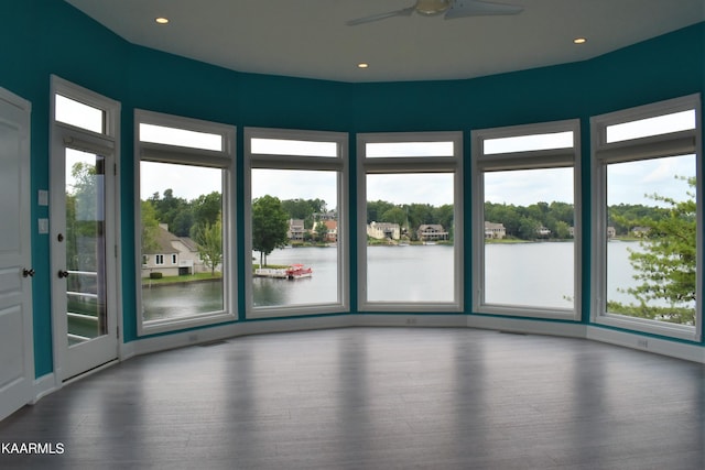 interior space with dark hardwood / wood-style flooring, ceiling fan, and a water view