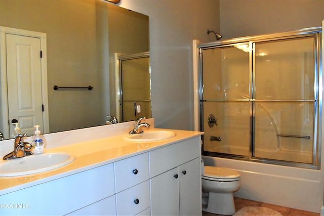 full bathroom with shower / bath combination with glass door, tile floors, toilet, and dual bowl vanity