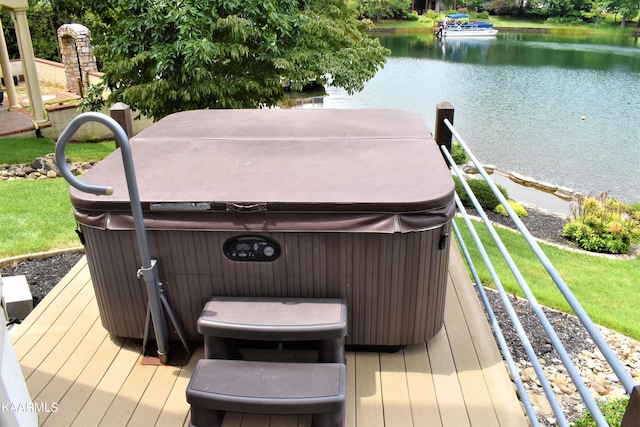 wooden terrace with a water view, a hot tub, and a yard