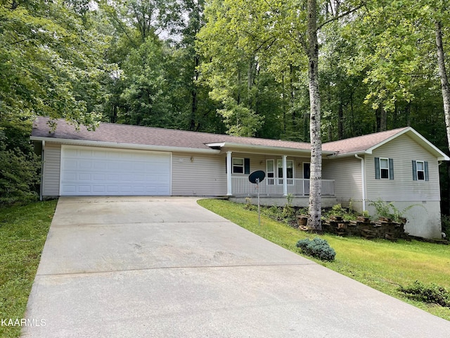 single story home featuring covered porch, a front lawn, and a garage