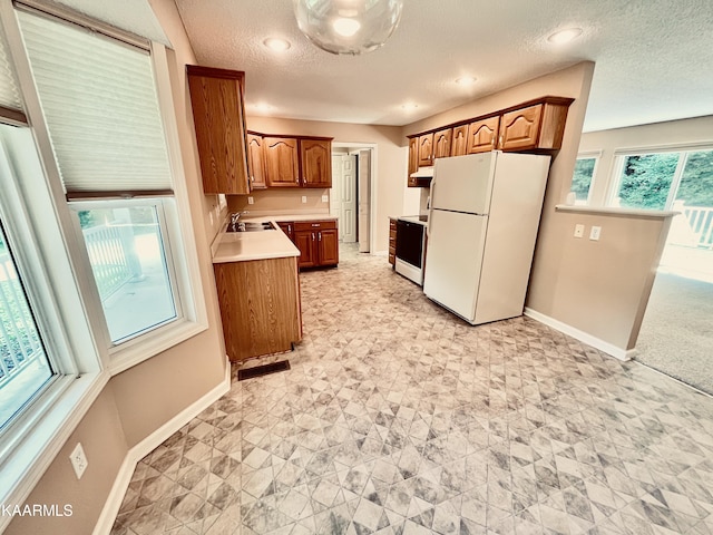 kitchen featuring white fridge, range with electric cooktop, light tile floors, a textured ceiling, and sink