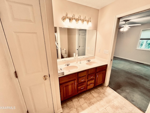 bathroom with ceiling fan, tile flooring, toilet, and dual bowl vanity