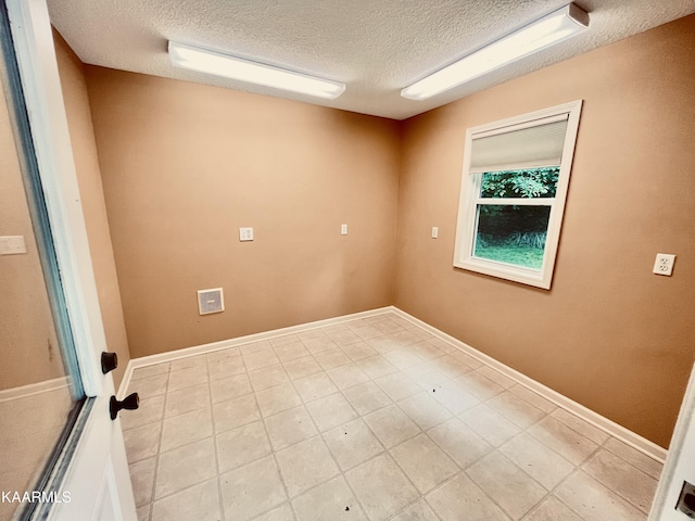 tiled spare room featuring a textured ceiling