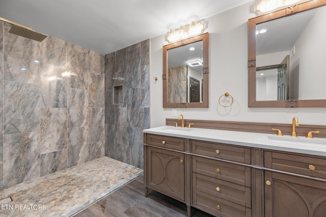 bathroom with vanity, a tile shower, and wood-type flooring