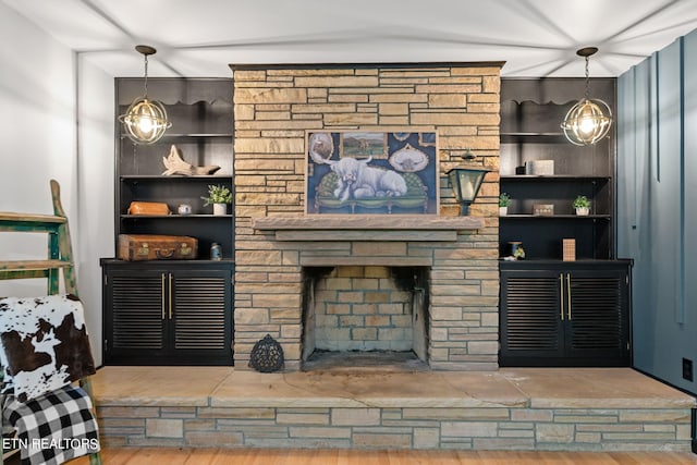 living room featuring built in features, wood-type flooring, and a fireplace